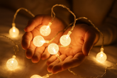 String lights held in hands with a warm glow